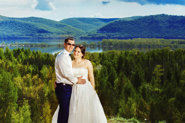 Happy beautiful bride and groom are embracing at top of hill