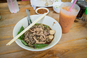 Noodles with pork and pork balls with soup Thai style on wood table