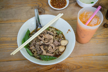 Noodles with pork and pork balls with soup Thai style on wood table