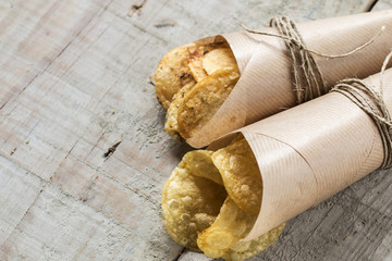 Potato chips with herbs in rustic cone with wooden background