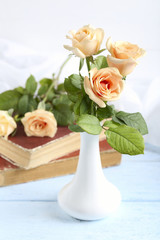 Bouquet of orange roses in vase on blue wooden background