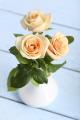 Bouquet of orange roses in vase on blue wooden background
