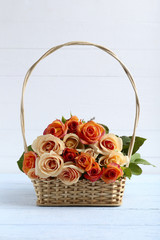 Fototapeta na wymiar Bouquet of orange roses in basket on blue wooden background