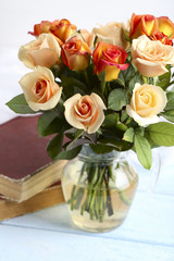 Bouquet of orange roses in vase on blue wooden background