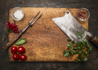 wooden cutting board with Slasher meat fork meat pepper salt tomatoes, fresh herb top view  on...