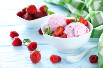 Ice cream in bowl with strawberries and raspberries on blue wood