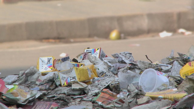 Close view of a pile of trash set on the side of a busy street.