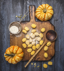 pumpkin gnocchi  with flour pumpkins spoon on a wooden cutting board on dark rustic background   top view