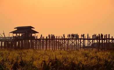 Amarapura, Myanmar - 14 March 2015: People walking on the wooden bridge of U Bein on river...