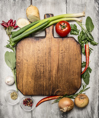 fresh autumn  and vegetables seasonings and hearbs around a wooden cutting board on bright, rustic wood background top view