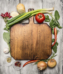 fresh autumn  and vegetables seasonings and hearbs around a wooden cutting board on bright, rustic...