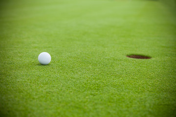 Golf ball next to hole