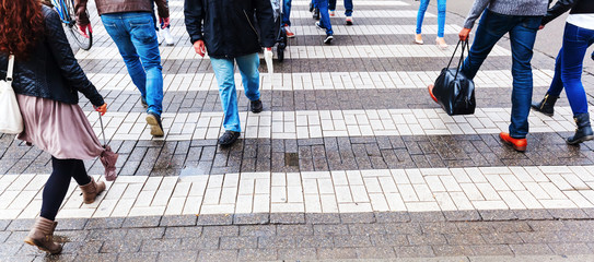 Menschen überqueren am Zebrastreifen die Straße