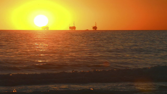 Winter sunset over the Pacific Ocean behind three oil platforms off of the Carpinteria coast near Santa Barbara, California.