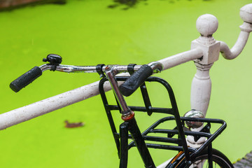 am Geländer eines holländischen Kanals lehnendes altes Fahrrad
