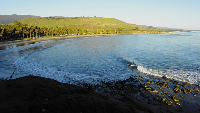 A solo surfer catching a wave at Refugio State Beach on the Gaviota Coast near Santa Barbara, California.