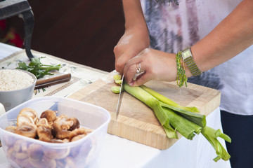 Woman cooking and slicing vegetable on cutting board.