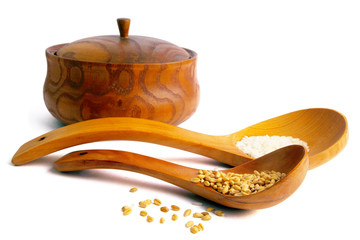 Wheat and rice on wooden spoon. Isolated on white.
