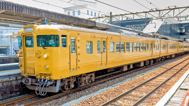 Fototapeta Japan train station with yellow railcars