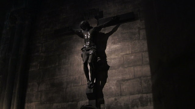 A spooky scene of Jesus on cross from a darkened church.