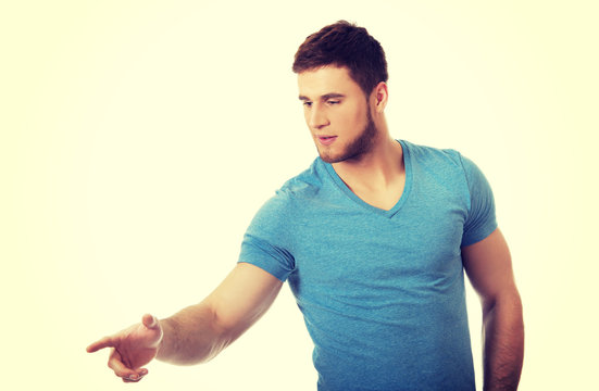 Handsome young man pointing down.