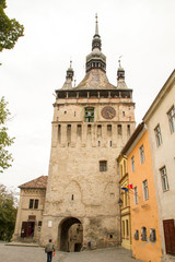 Fototapeta na wymiar The Clock Tower on medieval street of Sighisoara, Transylvania, Romania, 10 September 2015