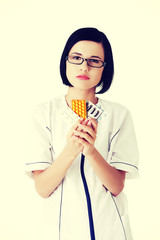 Female doctor in uniform holding pills