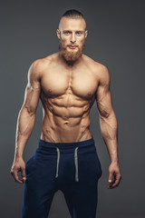 Fototapeta na wymiar Shirtless muscular guy posing over grey background.