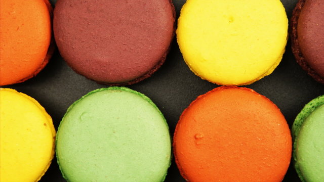 TRACKING: Top view of a Rows of Colorful Macaroons on a black table
