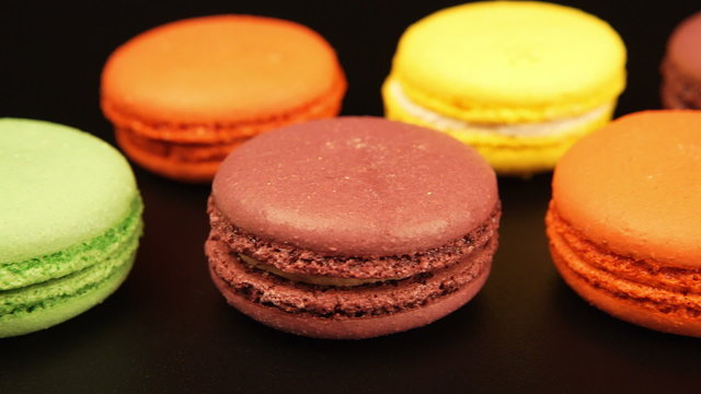 TRACKING: A rows of a colorful macaroons is on the black table
