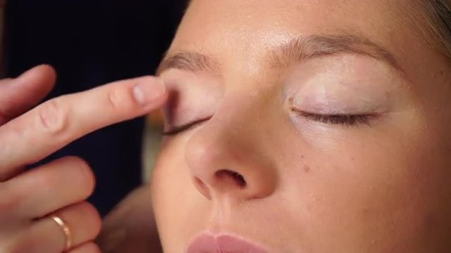 Makeup artist applying powder to model face 4K