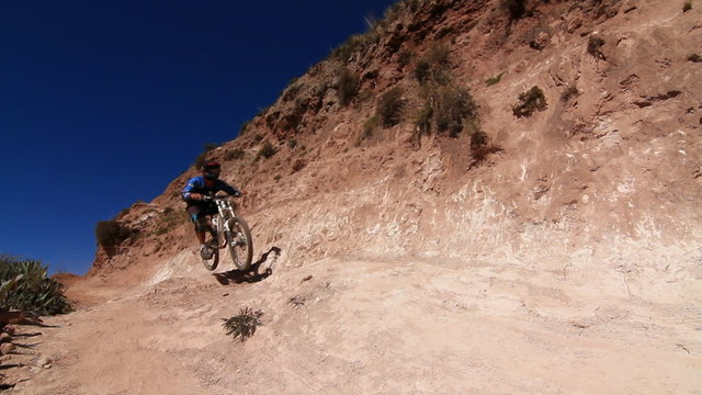 Biker Coming Around Bend And Going Over Jump