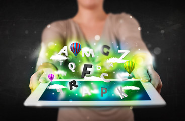 Young person showing tablet with abstract letters and sky