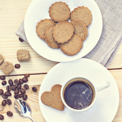 Ginger biscuits, cinnamon, a cup of hot coffee. Walnuts, hazelnuts on a wooden background. Tonned photo.