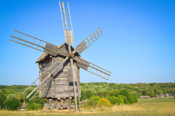 Fototapeta na wymiar Old windmill in the field under blue sky