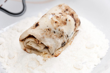 Stuffed rolled pancake in the flour ready for paning