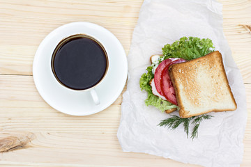 Sandwich and cup of black coffee on the table