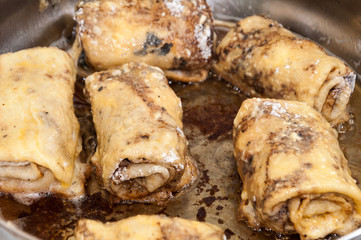 Frying rolled stuffed pancakes in hot oil