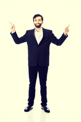 Happy businessman points his finger up.