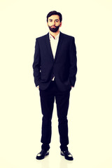 Smiling businessman with hands in pockets.