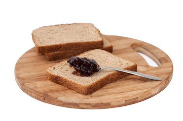 Strawberry jam on the metal spoon over bread