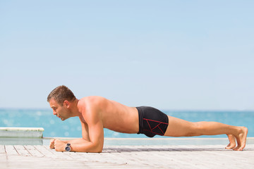 Fototapeta na wymiar Man doing plank exercise outdoors by the pool