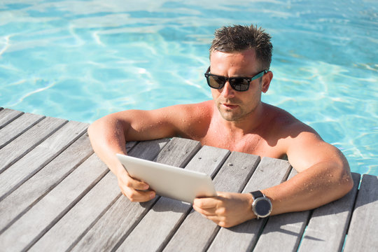 Man with digital tablet computer by the pool