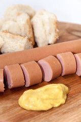 Sliced hot dog with mustard on the wooden board