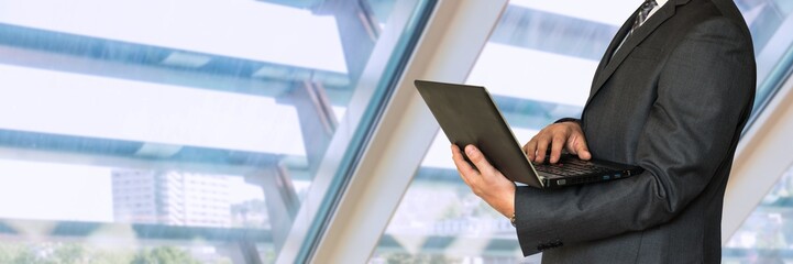 Businessman in black suit holding laptop