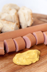 Sliced hot dog with mustard on the wooden board