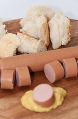 Sliced hot dog with mustard on the wooden board