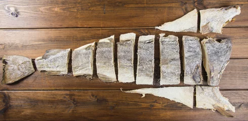 Fotobehang Corte tradicional en porciones del bacalao salado, pescado seco conservado en sal sobre fondo de madera © Angel Simon