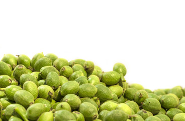A lot green young walnuts in husks on white background