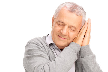 Cheerful senior sleeping on his hands and smiling